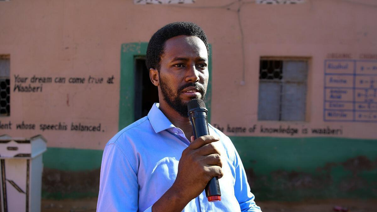 Mohamed Sheikh Said Haji speaks with a microphone in front of a school Mohamed Sheikh Said Haji speaks with a microphone in front of a school