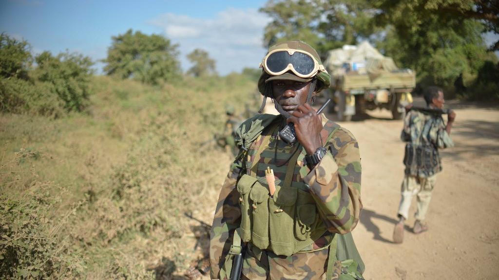 A man in military uniform speaking into a radio.