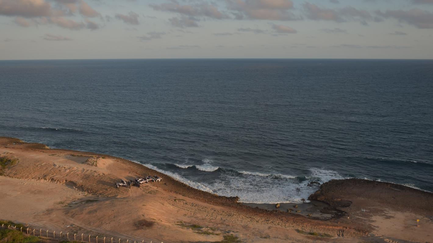 A photo of a beach in Somalia where some cars and people can be seen